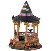 Lemax vista frontal del Witch Gazebo mostrando el sombrero de bruja y guirnalda de calabazas, ideal para decorar